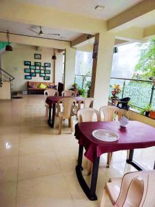 a dining room with tables and chairs and windows at Green Didis Cottage in Nagaon