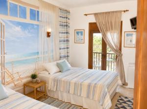 a bedroom with two beds and a large window at Hostal Bernareggi in Cala Figuera