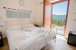 a bedroom with a white bed and a large window at Giardini Malaspina in Bosa