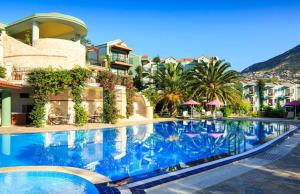 a swimming pool at a resort with palm trees and buildings at Kalkan Regency in Kalkan
