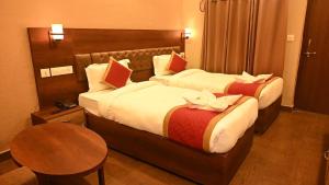 a hotel room with two beds and a table at Hotel Red Sapphire Kushinagar in Kushinagar