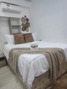 a white bedroom with a large bed with a blanket at Hotel Aquamarina Maicao in Maicao +12 photos