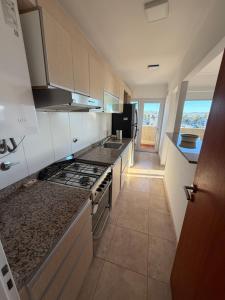 a kitchen with white cabinets and a stove top oven at LuxApart in Caleta Olivia