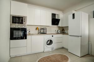 a kitchen with white cabinets and a washer and dryer at Ohrid Pearl Apartment in Ohrid