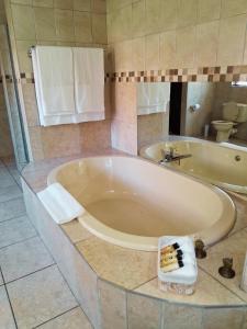 a large tub in a bathroom with a toilet at 30 on Latham Guesthouse in Klerksdorp +9 photos