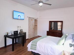 a bedroom with a bed and a desk with a television at 30 on Latham Guesthouse in Klerksdorp