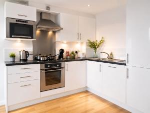 a white kitchen with stainless steel appliances and wood floors at York City Centre 1-bed Apartment Near Q-Park Parking - Best Location in York +15 photos