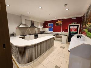 a large kitchen with white counters and red walls at Lyon House Hotel in Barking