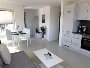 a white living room with a table and a kitchen at Haus am Wittenwiewerbarg in Dahme