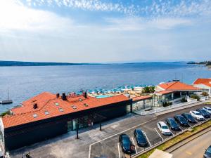 a building with cars parked in a parking lot next to the water at Hotel Millenium deluxe in Selce