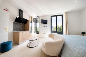 a bedroom with a bed and a chair and a tv at HDG Hôtel Gare de L'Isle Adam Appart's Hotel in Parmain