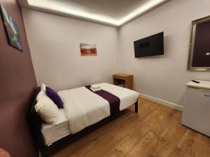 a small room with a bed and a tv at Lyon House Hotel in Barking