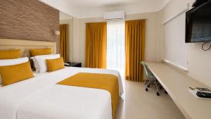 a bedroom with a bed and a desk and a television at Hotel Terras da Finlândia in Penedo