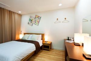 a bedroom with a bed and a desk with two lamps at The BB's Jeju Resort in Seogwipo