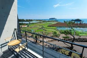 a balcony with a bench and a view of the ocean at The BB's Jeju Resort in Seogwipo