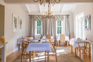 a dining room with tables and chairs and a chandelier at La Cabriere Country House in Franschhoek