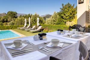a table with plates and utensils next to a pool at La Cabriere Country House in Franschhoek