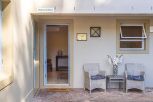 a hallway with two chairs and a table with a vase of flowers at La Cabriere Country House in Franschhoek +47 photos