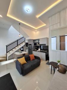 a living room with a black couch and a kitchen at Athara Naya in Karangploso