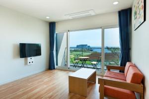 a living room with a couch and a tv at The BB's Jeju Resort in Seogwipo