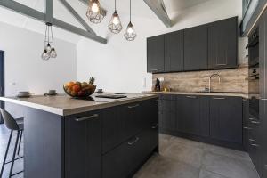 a kitchen with black cabinets and a bowl of fruit on the counter at Cozy Cottage with Spa - Welkeys in Moliets-et-Maa