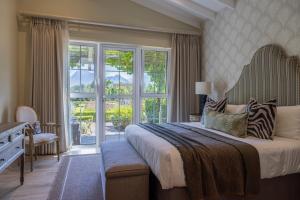 a bedroom with a large bed and a large window at La Cabriere Country House in Franschhoek