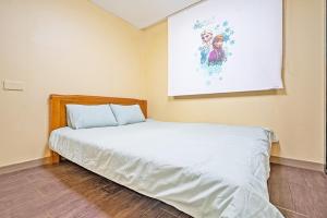 a bed in a room with a painting on the wall at Daebudo sunshine kids poolvilla in Ansan