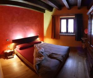 una camera con un grande letto con una parete rossa di B&B Scacciapensieri - Vini d'Altura a Colledara