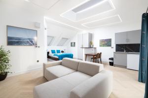a living room with a white couch and a kitchen at Harrow Boutique Suites in Harrow