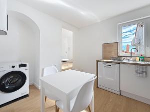a white kitchen with a table and a washing machine at 8C - L'Urban in Saint-Rambert-dʼAlbon