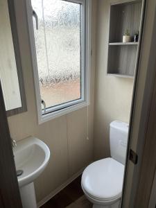 a bathroom with a toilet and a sink and a window at Linnet Moselle 5 in Peterhead +5 photos