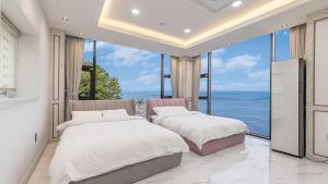two beds in a bedroom with a view of the ocean at yongdeok marryel poolvilla in Yŏngdŏk