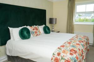 a bedroom with a large white bed with green pillows at Nesbitt Arms Boutique Hotel in Ardara