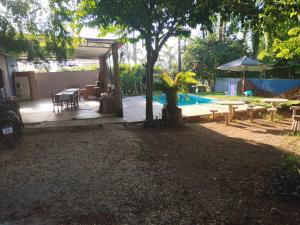 a patio with a table and an umbrella and a pool at Hostel Oasis Jaguariuna in Jaguariúna