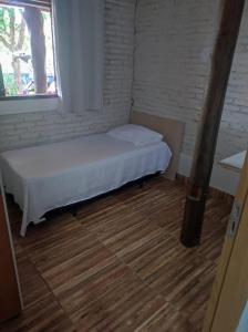 a small bed in a room with a window at Hostel Oasis Jaguariuna in Jaguariúna