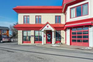 a store with red doors on the side of a street at Auberge l'Ambassadeur in Amqui