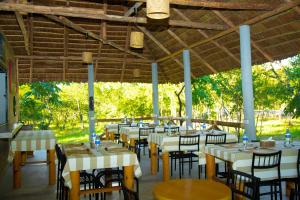 a restaurant with white tables and chairs and trees at FRAPG camp and lodge in Mikumi