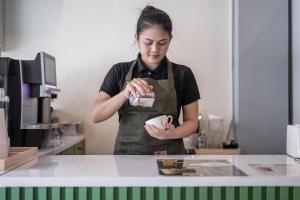 a woman standing in a kitchen preparing food at V Style Pattaya North Beach in Pattaya
