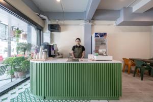 a woman standing behind a green counter in a room at V Style Pattaya North Beach in Pattaya