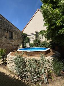 a swimming pool sitting next to a brick building at Le Logis du Coteau in Bellefoye
