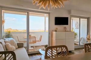 a living room with a couch and a table at Sable & Pampas - Meublé de Tourisme 5 étoiles - Vue Panoramique & Terrasse - Climatisation - Plage à 200m in Carnon-Plage +43 photos