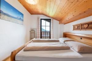 two beds in a room with a wooden ceiling at Gschtraffhof in Kastelruth