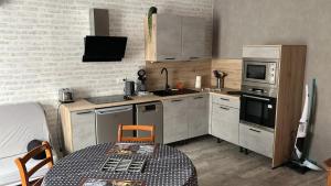 a small kitchen with a table and a microwave at Domaine Du Hêtre - Meublé T2 in Bains-les-Bains +12 photos