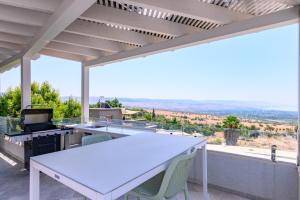 an outdoor kitchen with a white table and chairs at ציפור הכנרת - סוויטה מבודדת נוף לכנרת in Had Nes