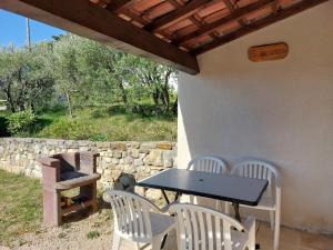 a table and chairs on a patio with a grill at Le Cyprès - La Fontinelle in Bessas
