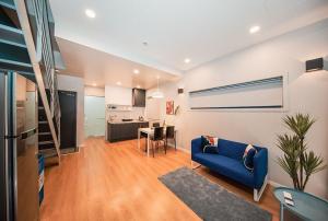 a living room with a blue couch and a kitchen at Daecheon Boryeong the Playa Pension in Boryeong