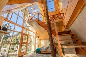 a loft bed in a room with a large window at jibhihomesteadcabin in Jibhi