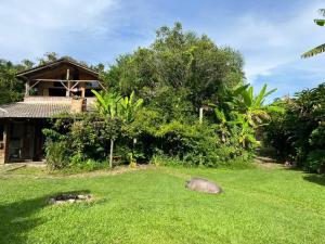 a green yard with a house in the background at Tudo é Arte Retreat - A Creative Haven Between Nature and Sea in Piçarras