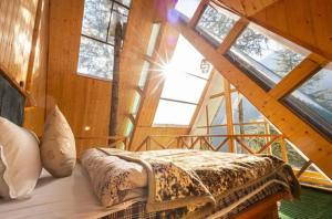 a bedroom with a bed in a room with windows at jibhihomesteadcabin in Jibhi +16 photos