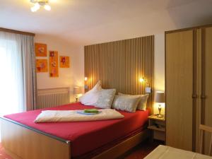 a bedroom with a large bed with red sheets and pillows at Gästehaus Judith in Längenfeld